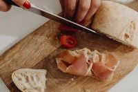 Kaboompics - Slicing Cherry Tomatoes Beside Prosciutto and Rustic Bread