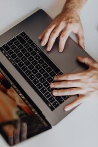 Kaboompics - Hands Typing on MacBook with DSLR Camera on Desk