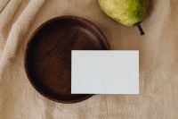 Kaboompics - Green Pear and Blank Business Card on Beige Linen beside a Dark Wood Plate