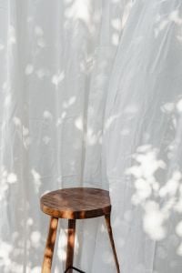 Kaboompics - Sheer Linen Curtains and Wooden Stool in Dappled Sunlight