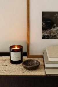 Kaboompics - Close-Up of Lit Candle, Stone Bowl and Neutral Books on Travertine Console