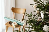 Kaboompics - Wrapped Gift and Paper on Chair beside Christmas Tree