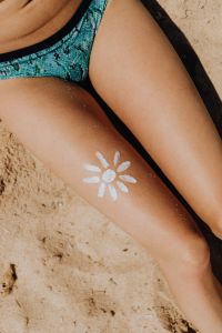 Kaboompics - Close-Up of White Sun Body Paint on Tanned Leg Against Beach Sand