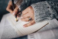 Kaboompics - Woman in a grey sweater taking notes in an organizer