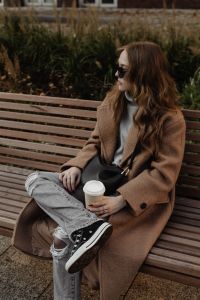 Kaboompics - Woman in Sunglasses Sitting with Coffee on a Curved Wooden Bench