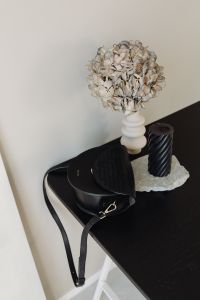 Kaboompics - Black Leather Shoulder Bag, Spiral Candle and Dried Hydrangea on Dark Desk