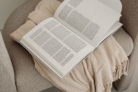 Kaboompics - Open Book and Fringed Throw on Beige Armchair, Overhead View