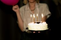 Kaboompics - Woman Presenting a Candlelit Cake with Retro Birthday Nostalgia