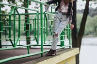 Kaboompics - Blonde woman in a black jacket and ripped jeans by a green handrail