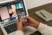 Kaboompics - Hands Viewing Instagram on Smartphone Beside Laptop