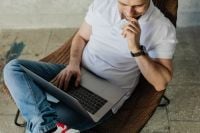 Kaboompics - The man is sitting in a chair and working with a laptop