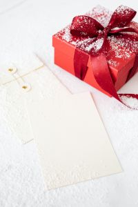 Kaboompics - Blank Christmas Card Beneath a Red Gift Box with a Snow-Dusted Satin Bow