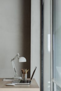 Kaboompics - Vertical Wooden Desk Detail with White Lamp, Pencil Pot and Partly Visible Laptop