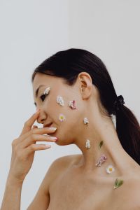 Kaboompics - Asian Woman Touching Her Face with Small Flowers on Cheek and Neck