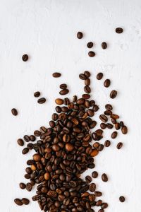 Kaboompics - Sparse Coffee Beans on White Plaster with Vertical Copy Space for Coffee Packaging