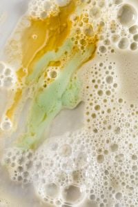 Kaboompics - Sage Green and Golden Skincare Cream Streaks Across a Foamy Texture