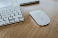 Kaboompics - White Apple Mouse and Keyboard on a Light Wood Computer Desk, Minimal Office Close-Up