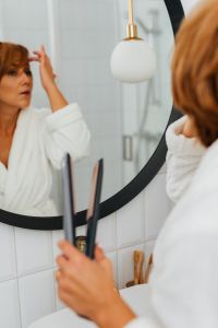 Kaboompics - Woman Checking Her Short Hair in a Bathroom Mirror While Holding a Flat Iron