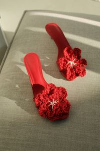 Kaboompics - Two Red Crochet-Flower Sandals on Gray Upholstery, Vertical Sunlit Fashion Photo
