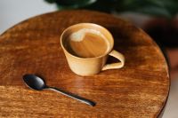 Kaboompics - Close-Up Beige Coffee Cup with Black Spoon on Wooden Table