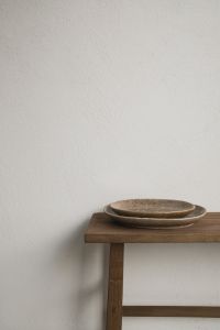 Kaboompics - Wooden Bench with Ceramic Plates Against Textured White Wall