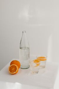 Kaboompics - Close Arrangement of a Water Bottle, Two Orange-Slice Glasses and Fresh Citrus on White Linen