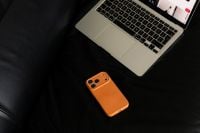 Kaboompics - Open Laptop and Orange Smartphone on Black Leather Sofa
