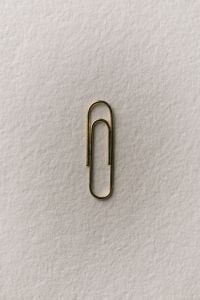 Kaboompics - Gold Paper Clip on Textured White Background