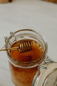 Kaboompics - Overhead Amber Honey and Metal Dipper in a Glass Jar, Minimal Food Background with Copy Space