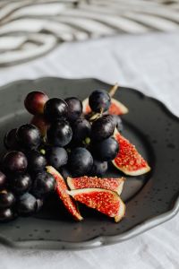 Kaboompics - Dark Grapes and Fig Wedges on a Black Plate with Striped Linen