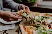 Kaboompics - Cheese-Topped Pizza Slice Held Above a White Plate