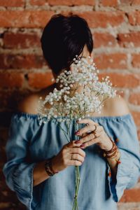 Kaboompics - A woman in a blue dress holds a branch of Baby's Breath flower
