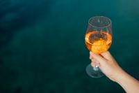 Kaboompics - Close Handheld Aperol Spritz against Teal Sea