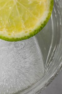 Kaboompics - Cropped Lime Wheel and Ice Cube in Clear Water, Extreme Macro with Curved Glass Reflections