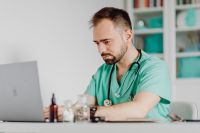 Kaboompics - Doctor Writing at Desk With Medical Supplies