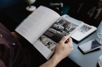Kaboompics - Person Reading a Magazine at a Desk with Laptop and Phone
