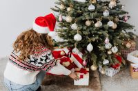 Kaboompics - Woman Reaching for Christmas Gifts Under a Decorated Tree