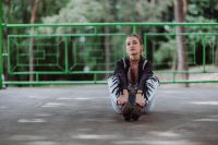 Kaboompics - Blonde woman in a black jacket and ripped jeans by a green handrail