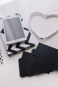 Kaboompics - Close-Up Smartphone and Heart-Shaped Cable on Black-and-White Notebook, Vertical Stationery Flat Lay