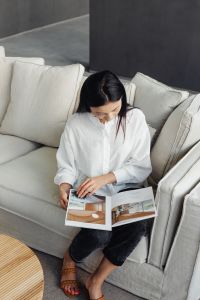 Kaboompics - Woman Seated on a Sofa Reading a Magazine