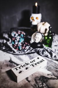 Kaboompics - Halloween Tabletop with Lit Candle, Skull Decor, White Pumpkin and Treat Sign