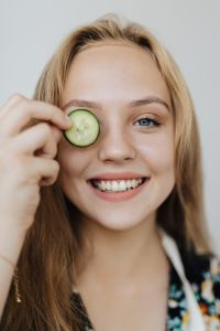 Kaboompics - Smiling Woman Holding a Cucumber Slice over One Eye