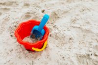 Kaboompics - Red Sand Pail and Blue Shovel on Textured Beach Sand for Kids' Summer Play