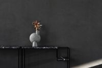 Kaboompics - Minimalist Black Marble Console Table with Sculptural Gray Vase and Dark Wall