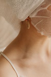Kaboompics - Close-Up Sheet Mask and Gold Earring Beneath a White Towel