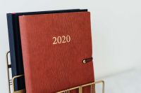 Kaboompics - Red 2020 Planner in Gold Rack on Marble with White Space