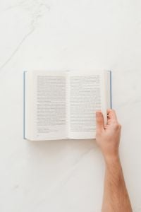 Kaboompics - Hand holding open book on marble table