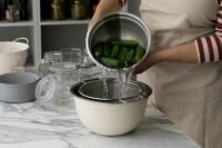 Kaboompics - Draining Small Cucumbers through a Colander over a Bowl on Marble Counter