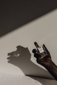 Kaboompics - Hand Holding a Dark Perfume Bottle Against a Light Wall
