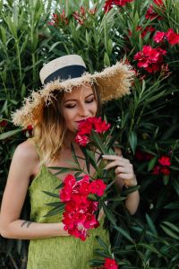 Kaboompics - Close-Up Portrait of a Woman Smelling Pink Flowers in a Straw Hat